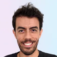 Marcelo smiling at the camera, with light blue and light ping background.